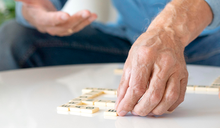 A senior reading a large-print book in a well-lit lounge, highlighting support at an Old age home for seniors with sight and hearing challenges near Delhi.
